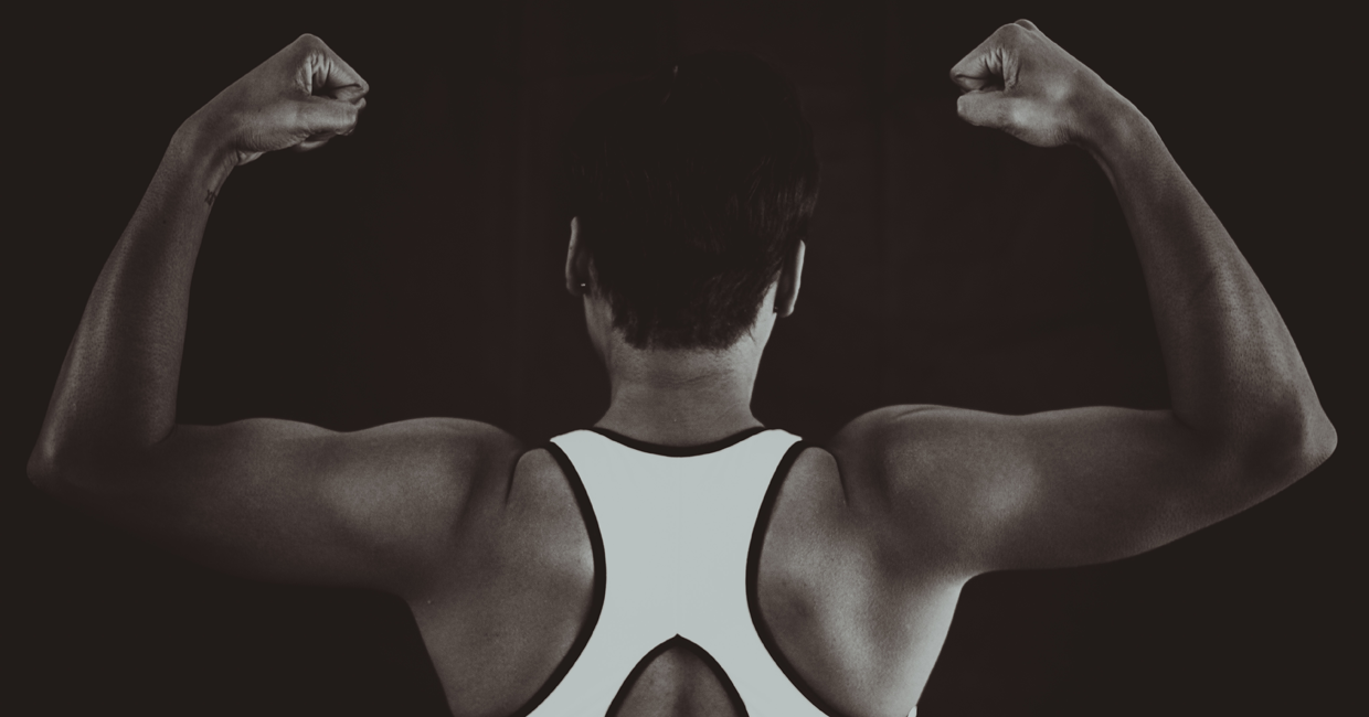 black and white photograph of women flexing her muscles in studio